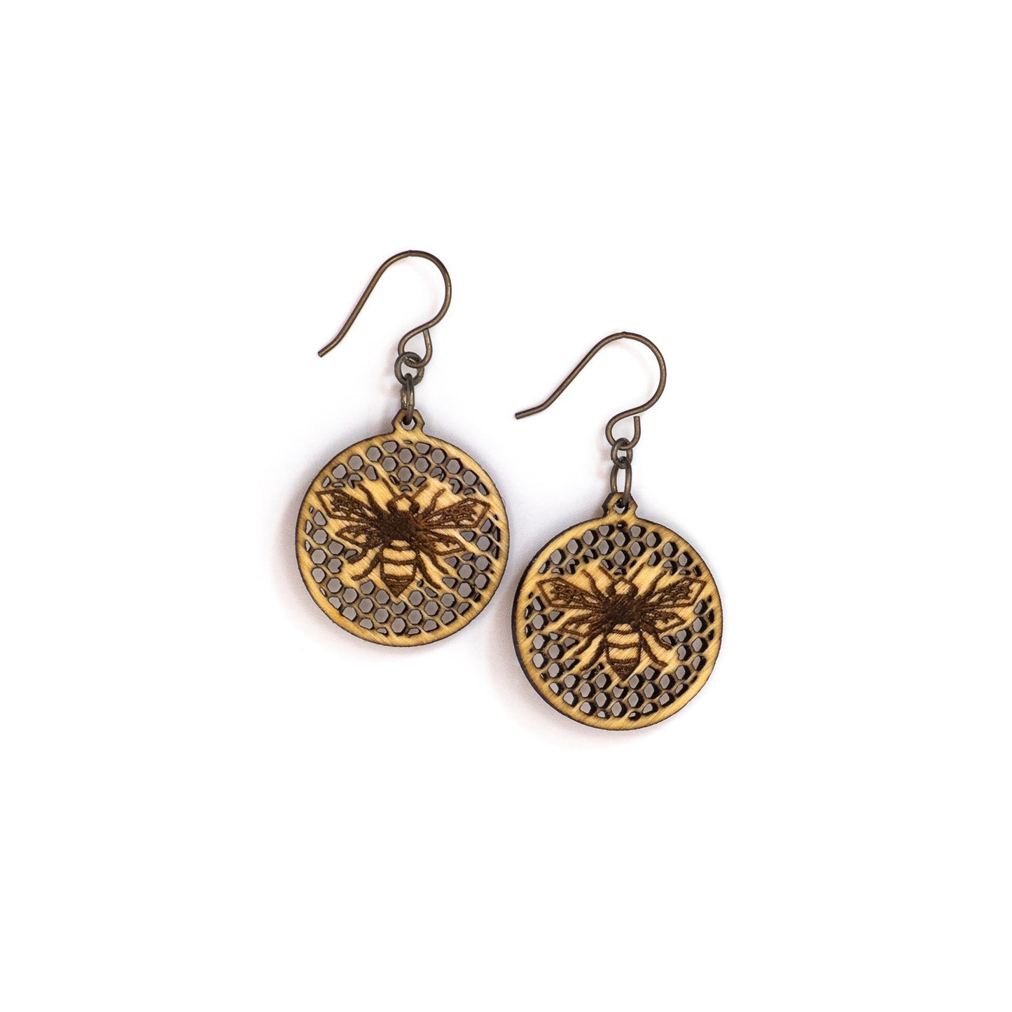 Two small round birch wood earrings, each depicting a laser etched honey bee on a background of many tiny hexagon holes. The bee is in flight as though viewing from above, it's wings spanning left to right and body positioned vertically up the center of the round discs.