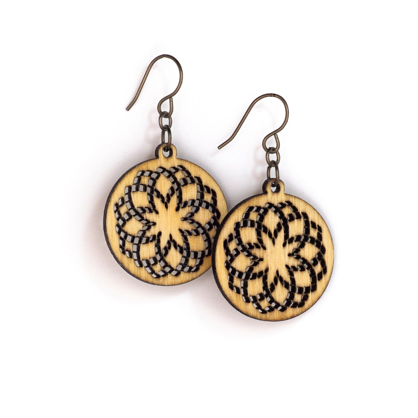 Two small round birch wood earrings with a laser cut design. The design is illustrative of sacred geometry with repeating circles creating a fractal effect loosely resembling a flower with an eight pointed star in the center.
