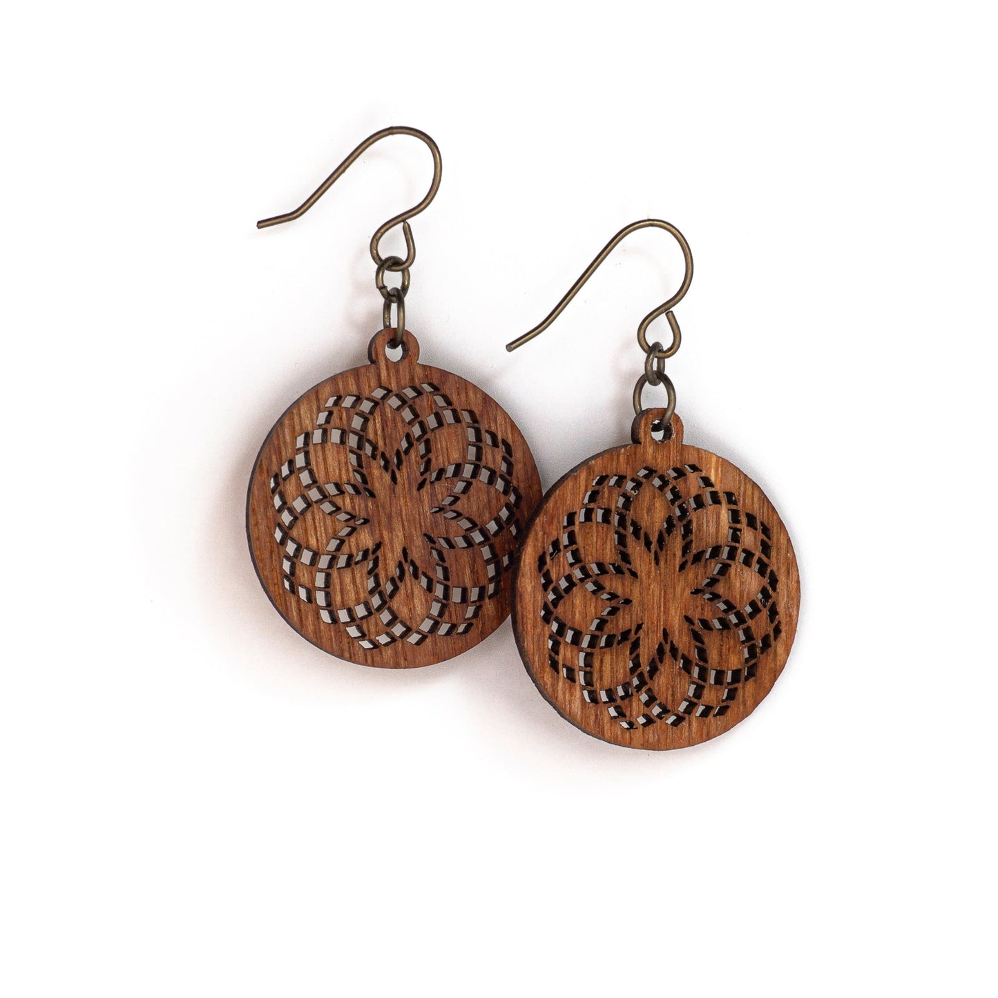 Two small round mahogany wood earrings with a laser cut design. The design is illustrative of sacred geometry with repeating circles creating a fractal effect loosely resembling a flower with an eight pointed star in the center.
