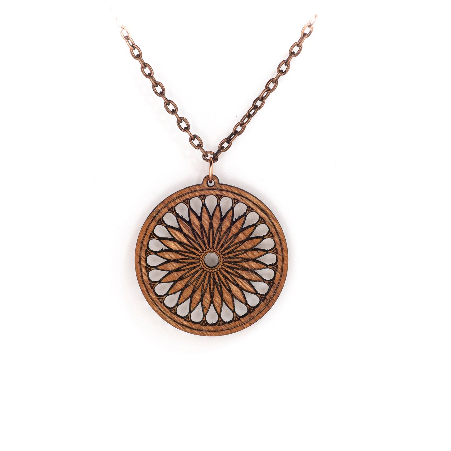 A delicate copper chain hangs in a 'V', at its apex is a round mahogany pendant. The pendant's face boasts a sacred geometric design, a repeating shape which fractals and loosely resembles a cross section of a citrus fruit or a 24 petalled daisy.
