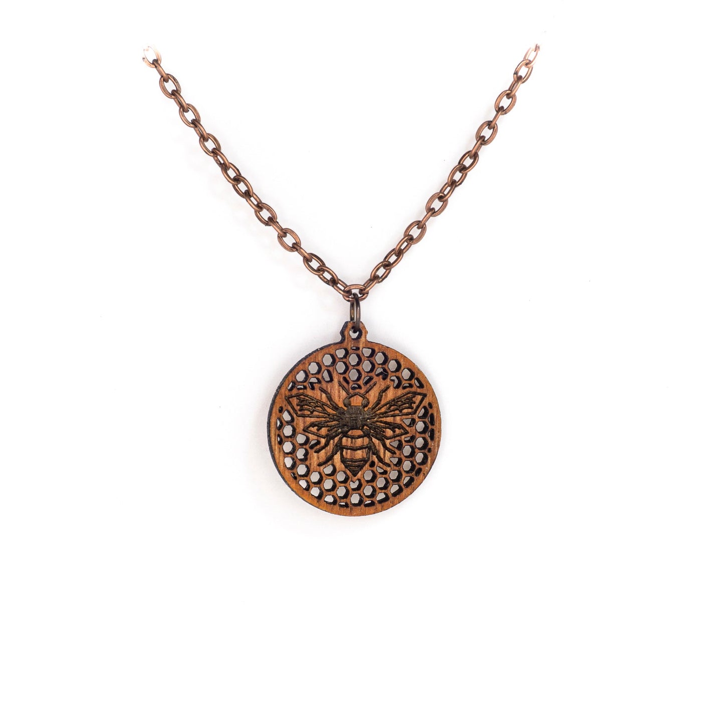 A delicate copper chain hangs in a 'V' shape. At its apex hangs a small round mahogany wood pendant, upon its face a laser etched honey bee on a background of many tiny hexagon holes. The bee is in flight as though viewing from above, it's wings spanning left to right and body positioned vertically up the center of the pendant.