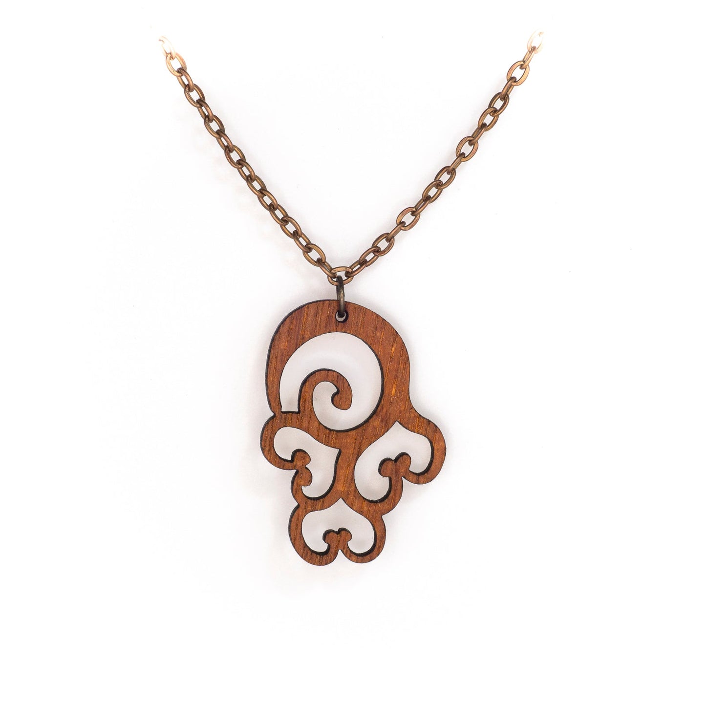 A delicate copper chain hangs in a 'V', at its apex is a small mahogany wood pendant. The pendant is an abstract design loosing forming a laser cut swirl with three laser cut upside down hearts seeming to dangle beneath it. The thick curving lines are emotive of billowing clouds and sensuous curves.